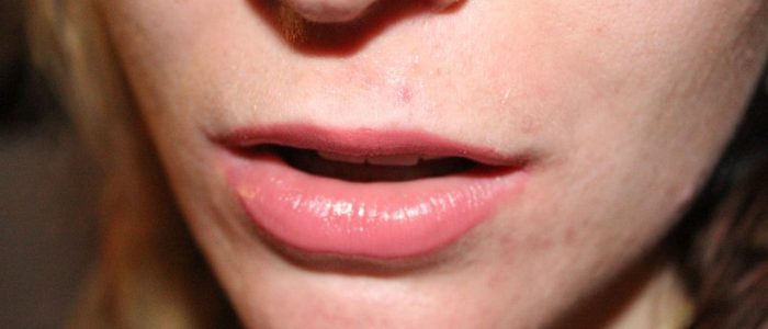 Närbild på en person med rosa läppstift och lätt öppen mun.